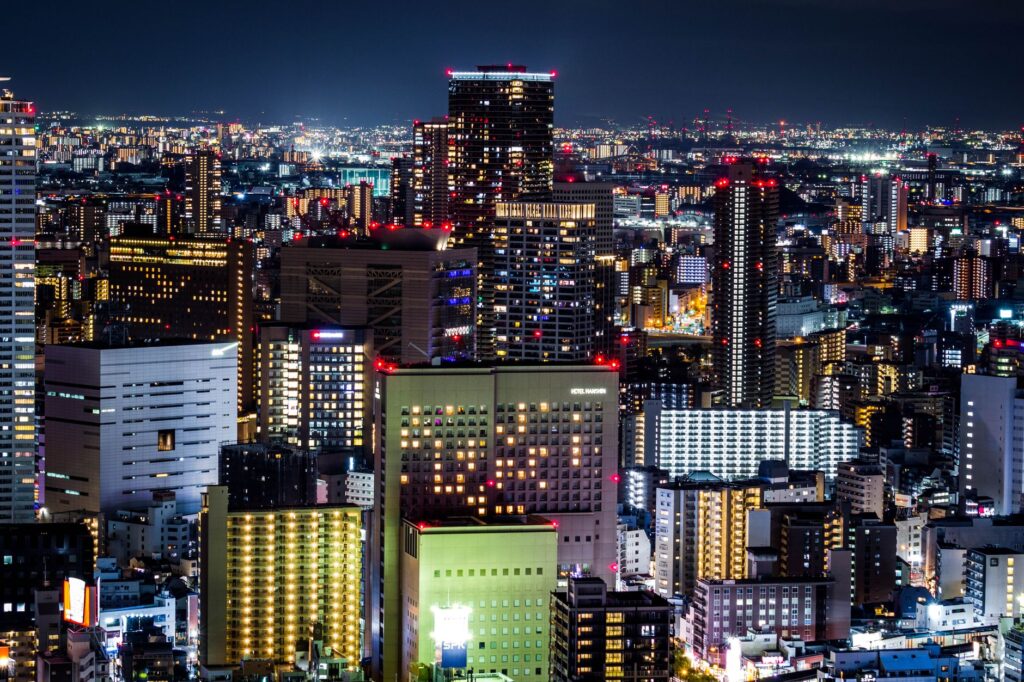 A dazzling view of Osaka's skyline at night featuring modern skyscrapers and glowing city lights.