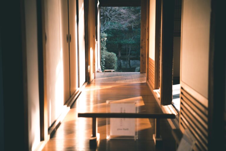 A tranquil Japanese interior hallway with wooden floors and sliding doors illuminated by sunlight.