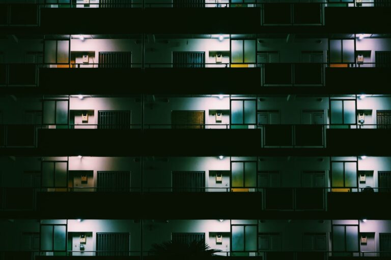 A nighttime view of a modern Tokyo apartment building with glowing lights and geometric patterns.