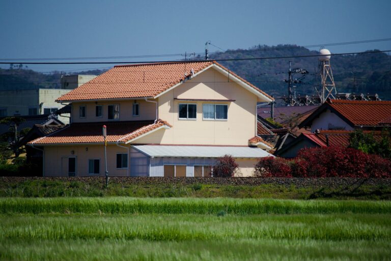 A serene countryside view featuring a house with a red tiled roof surrounded by greenery and hills.