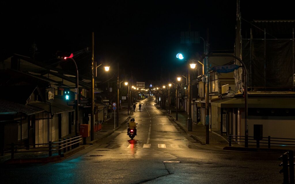 A tranquil night scene in Arashiyama, Kyoto, with streetlights and a lone motorbike.