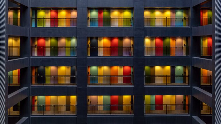 Vibrant multi-colored doors on a modern Tokyo apartment building facade at night.