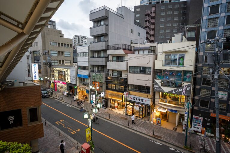 Street view of a vibrant Tokyo neighborhood at dusk, showcasing local shops and urban life.