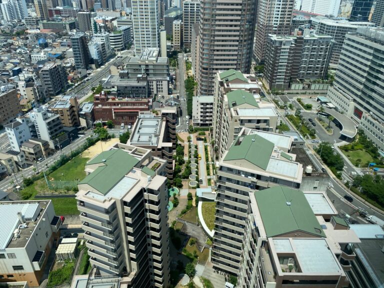 Aerial cityscape of high-rise apartments and streets under bright daylight.