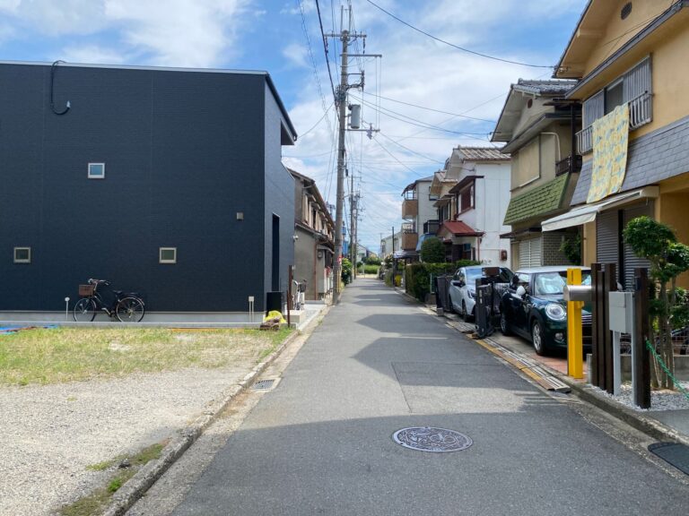 Peaceful urban residential street with houses and parked cars on a sunny day.