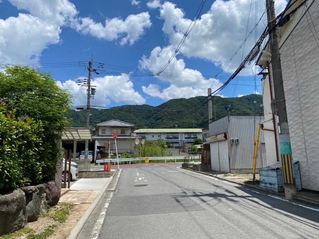 Sunny day view of a quiet suburban street with lush mountains in the background.