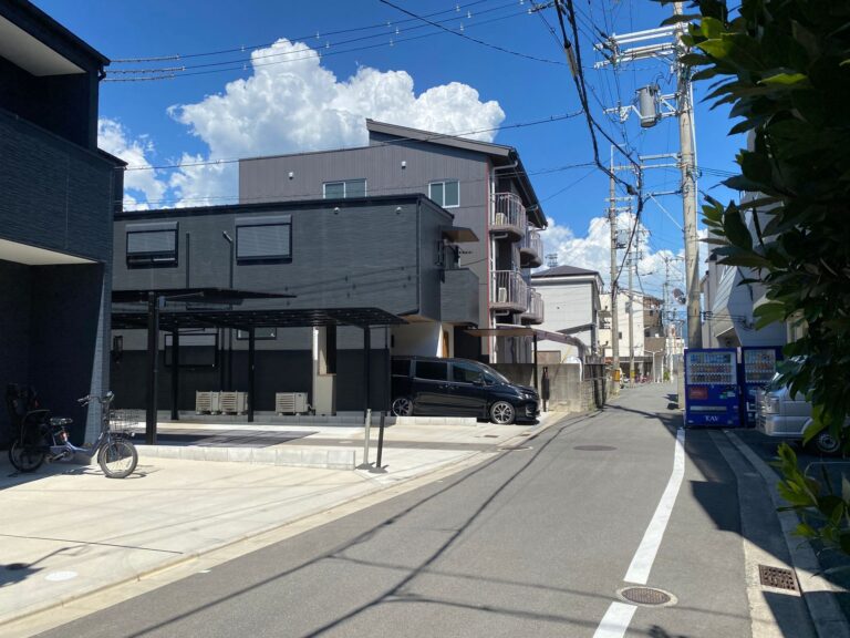 Sunny street in a Japanese neighborhood with modern residential buildings and a clear blue sky.