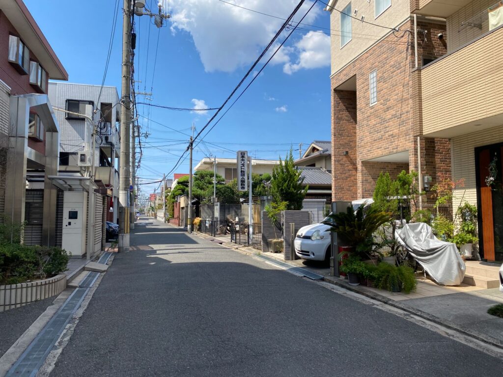 Peaceful urban street view with clear blue sky, modern buildings, and parked cars.
