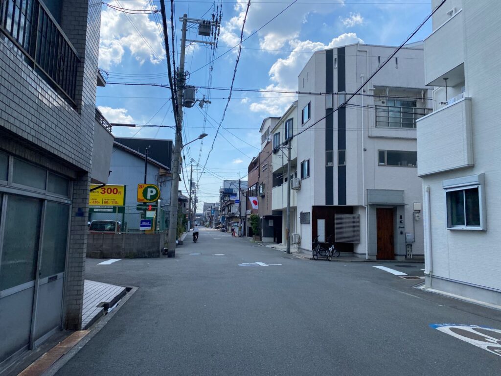 Empty street in a Japanese neighborhood with modern buildings and blue sky.
