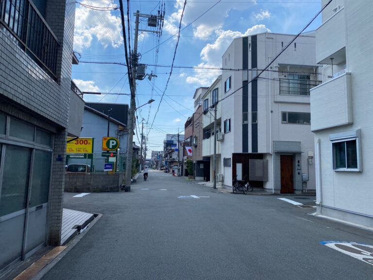 Empty street in a Japanese neighborhood with modern buildings and blue sky.