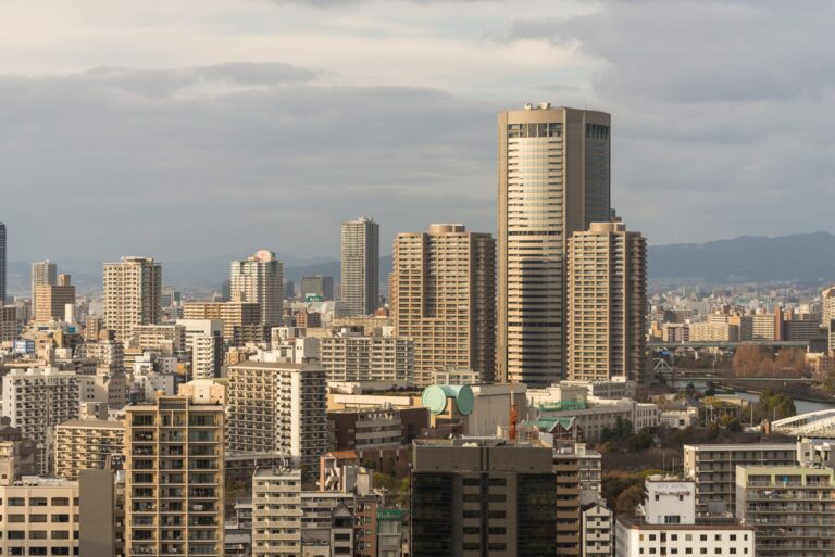 A breathtaking view of Osaka's urban skyline showcasing high-rise buildings under a cloudy sky.