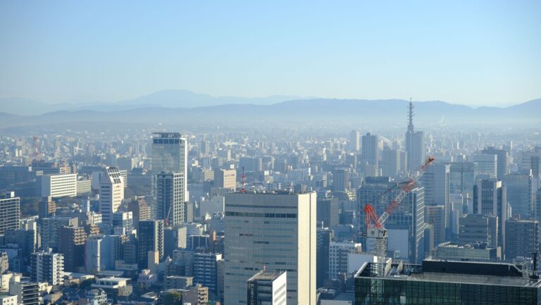 Breathtaking view of Osaka cityscape with skyscrapers and mountains in the background.