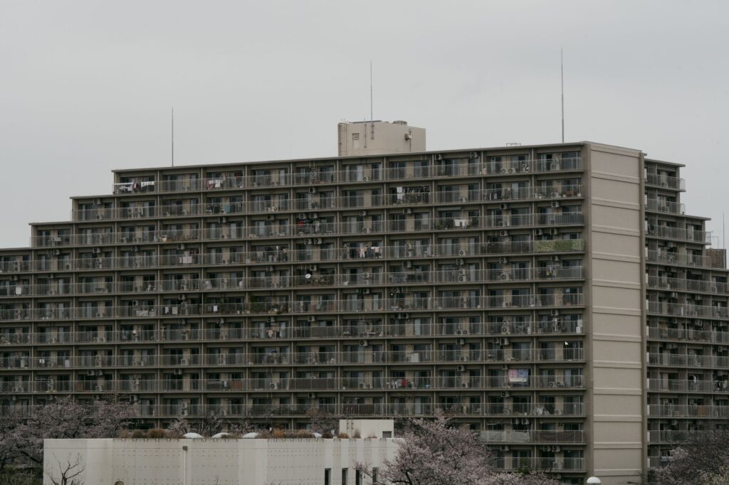 High-rise apartment building in Tokyo with cherry blossoms at the front, illustrating urban life in Japan.