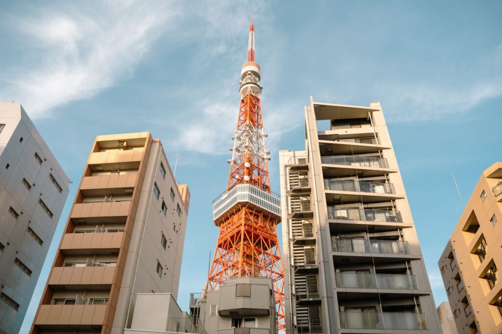 View of Tokyo Tower surrounded by modern apartments under a clear blue sky.