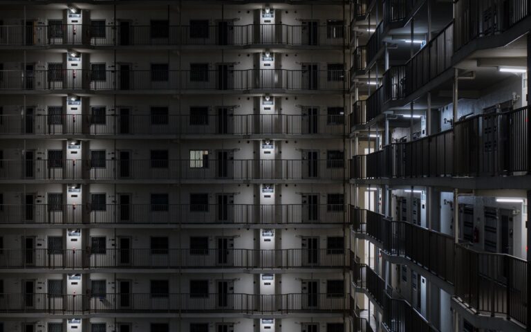 Illuminated view of a modern apartment building facade in Kyoto at night.