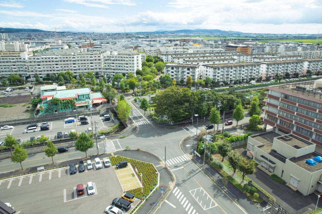 Scenery of contemporary city district with modern apartment buildings and vast parking area amidst green lush trees situ