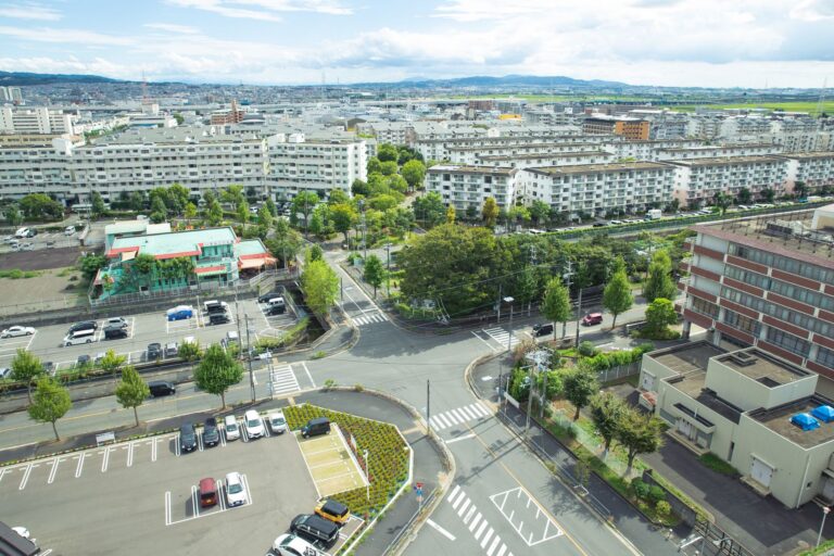 Scenery of contemporary city district with modern apartment buildings and vast parking area amidst green lush trees situ