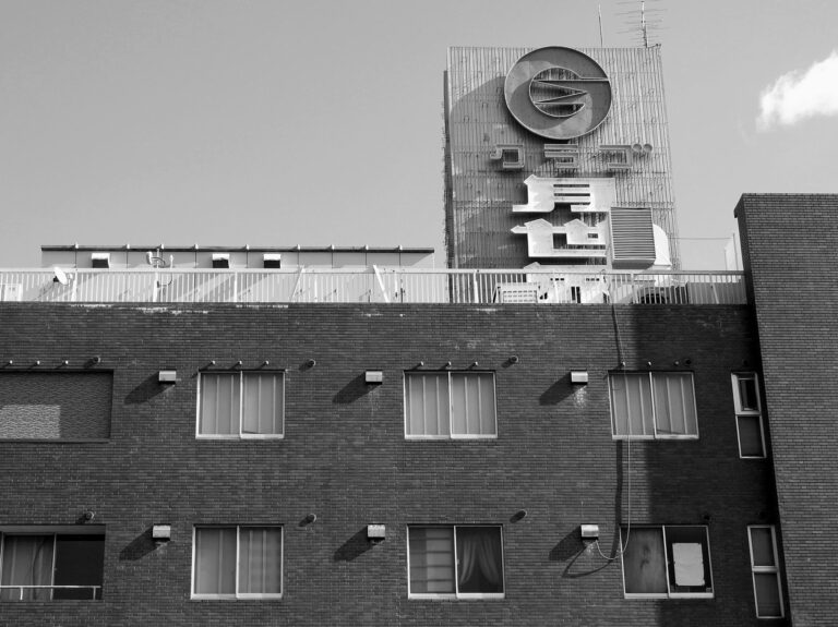 Black and white facade of modern residential building with brick walls and white windows on sunny day in city