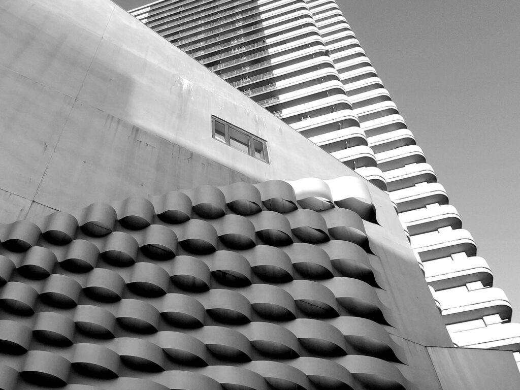 Low angle of contemporary multistory buildings with curvy balconies against cloudless sky on sunny day in modern city di