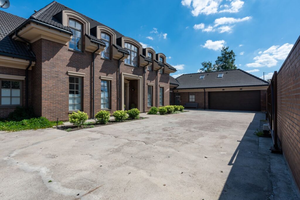 Elegant brick house exterior with a large driveway under a clear blue sky.