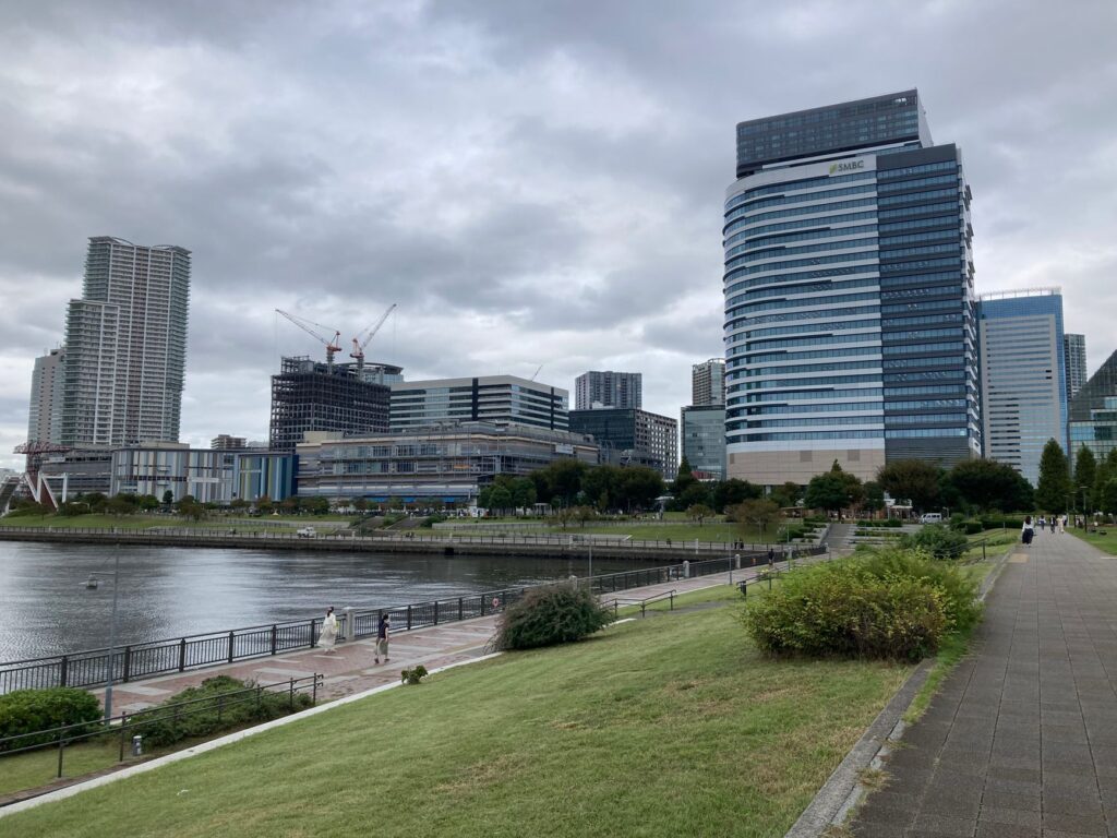 Overcast cityscape of Tokyo's waterfront featuring modern architecture and a serene river pathway.
