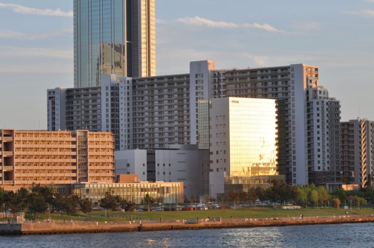 Contemporary cityscape featuring high-rise buildings and waterfront park during sunset.