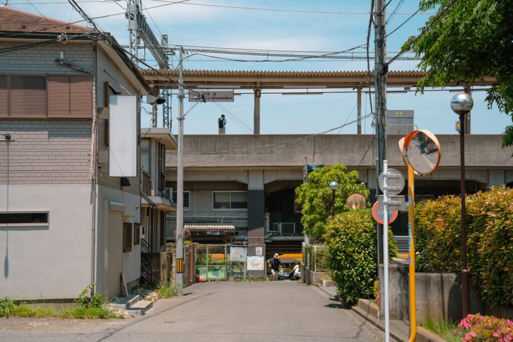 A sunny day street view of a suburban neighborhood in Hachiōji, Tokyo, showing urban architecture.
