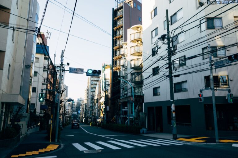 A bustling urban street in Tokyo, showcasing architecture, wires, and a pedestrian lane.