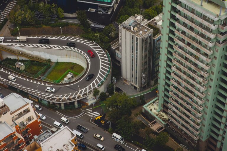 From above of modern city with tall buildings and cars rushing on asphalt roads